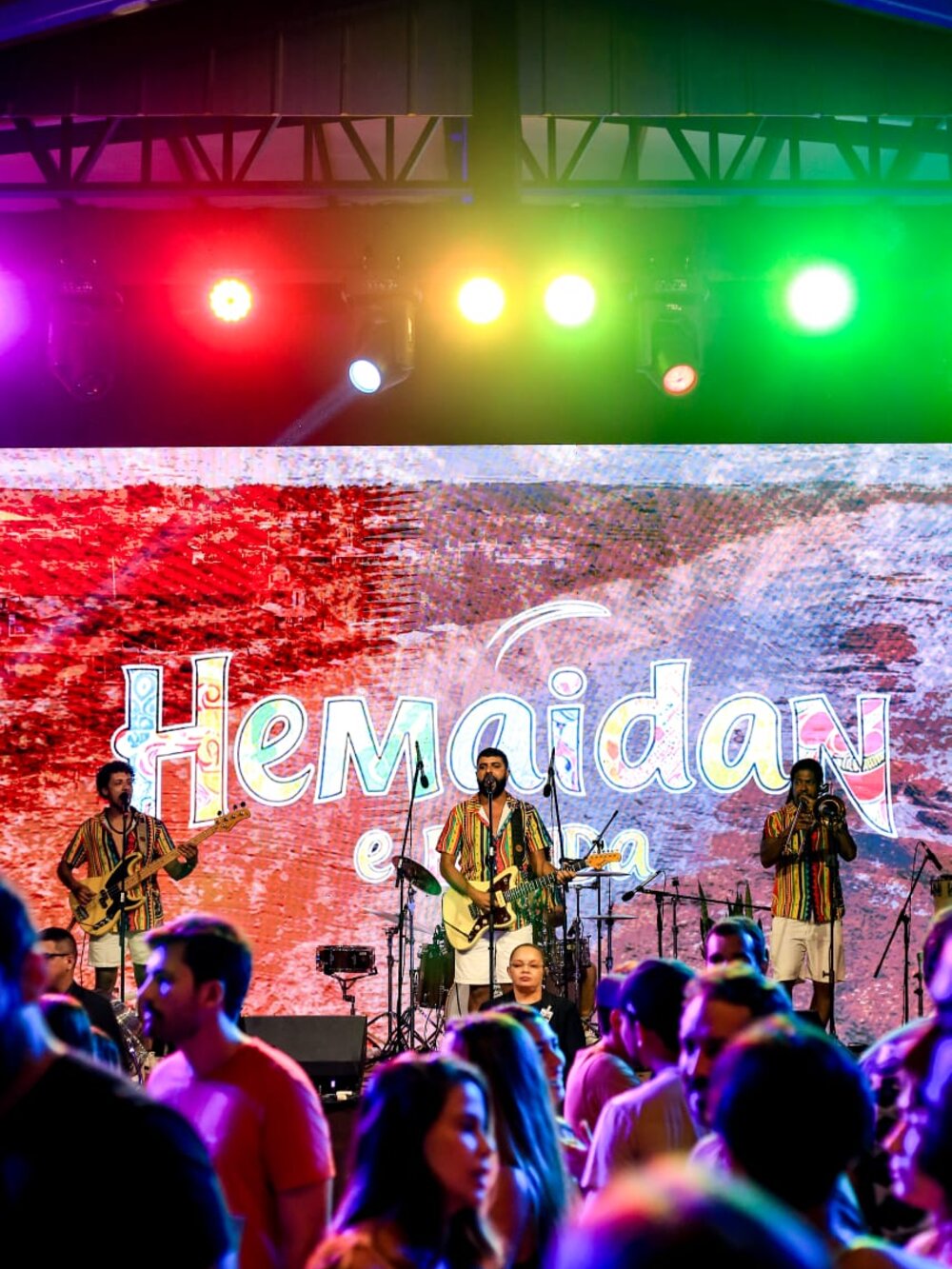 Hemaidan e Banda no palco, com o painel de LED da banda ao fundo e o público na frente